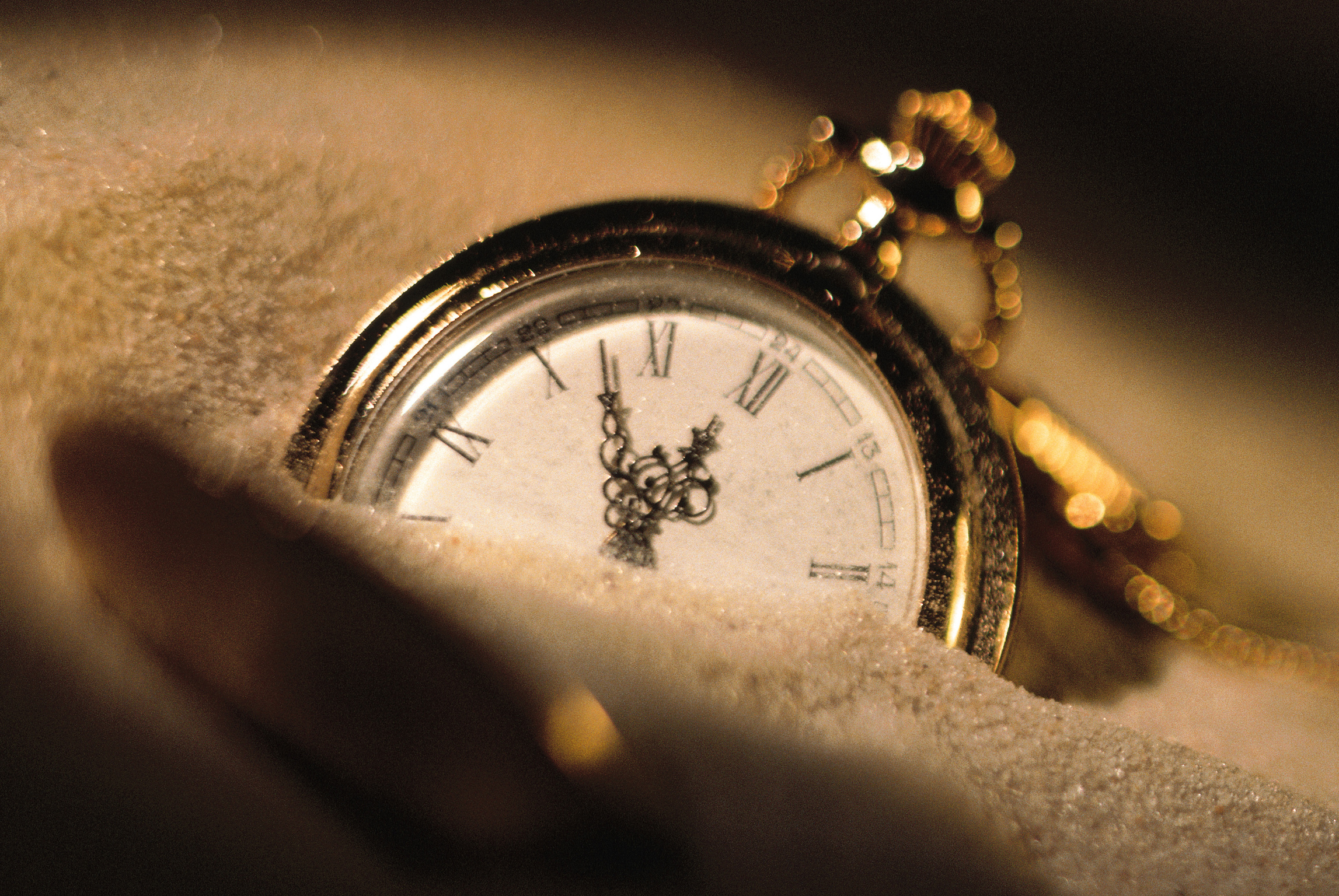 Pocket watch buried in sand